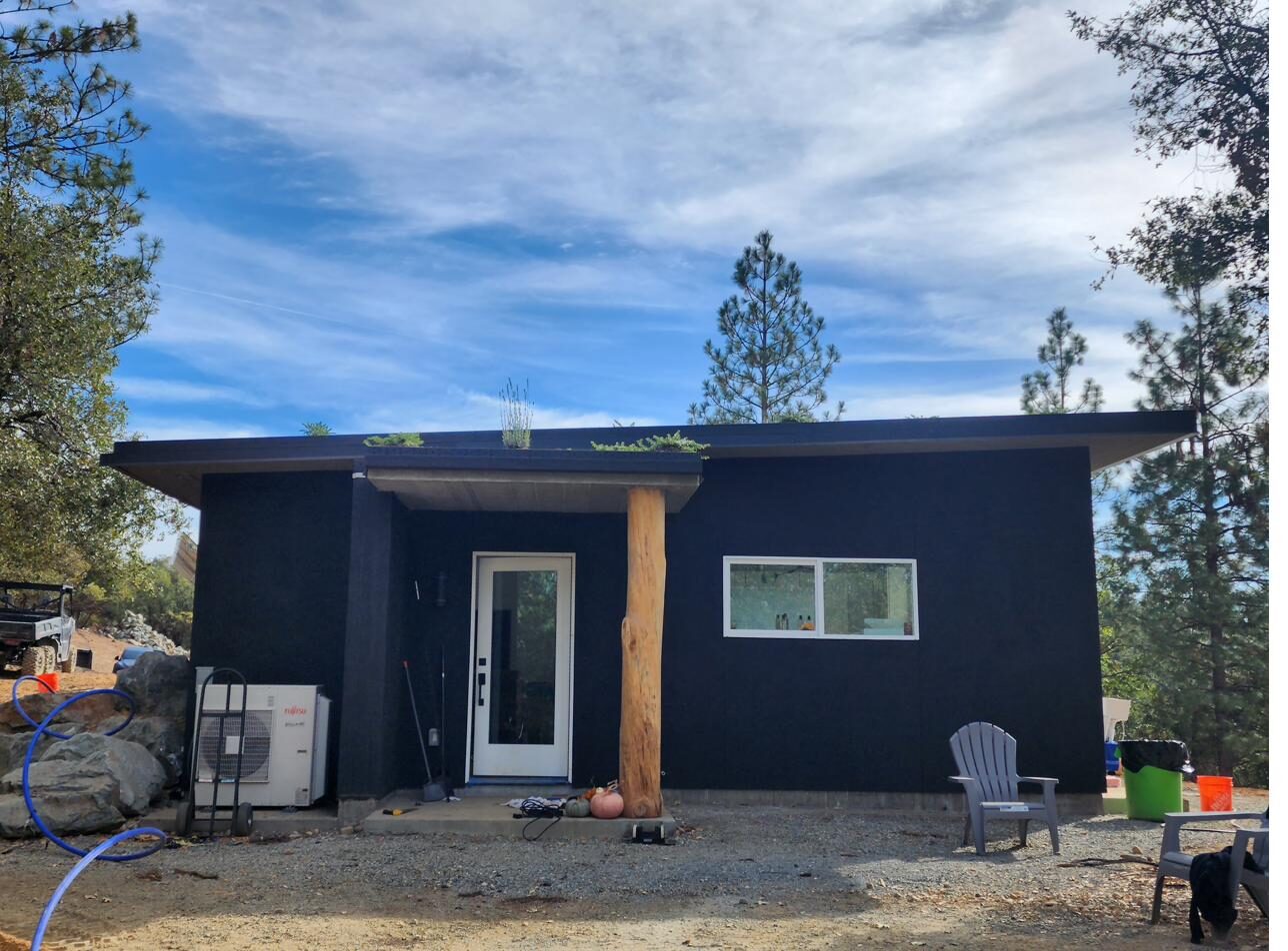 Finished home front exterior with natural log column and green roof edge