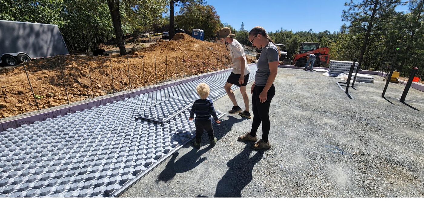 Family standing on gridded foam insulation panels for a radiant-heat concrete slab