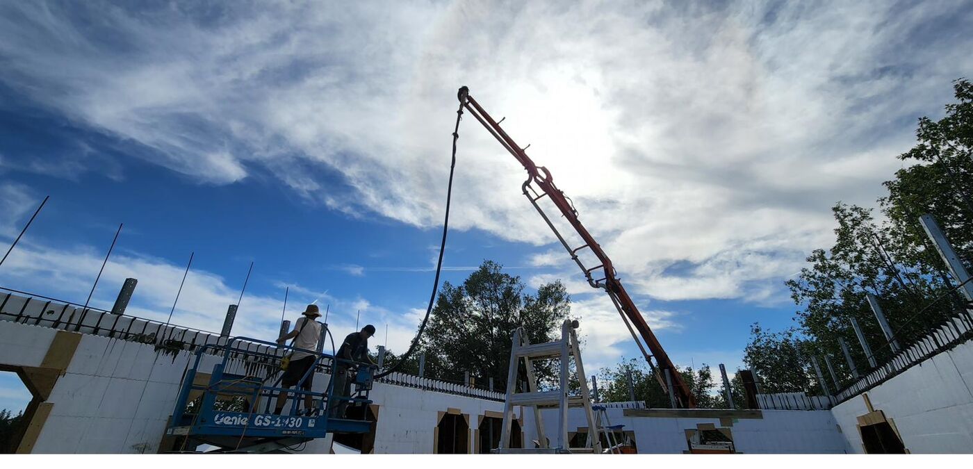 Concrete pump truck boom extended to fill ICF wall forms with a continuous pour
