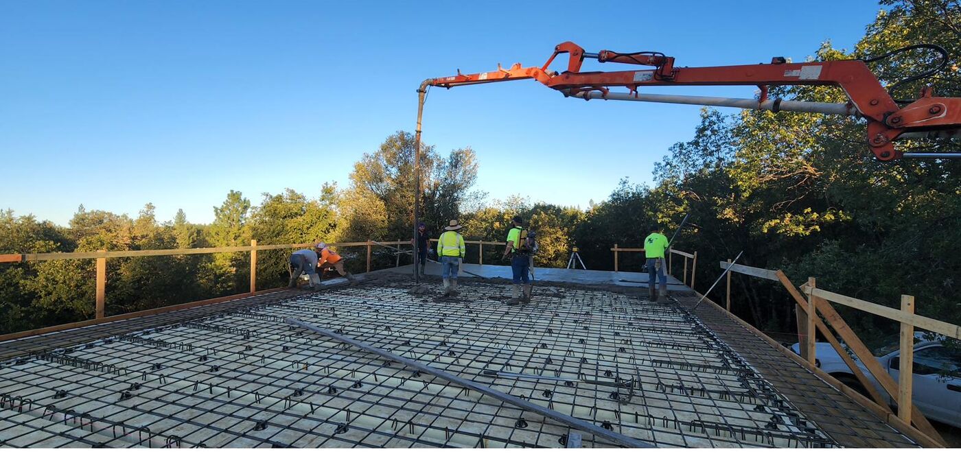 Five-person crew pouring a concrete roof slab at sunrise