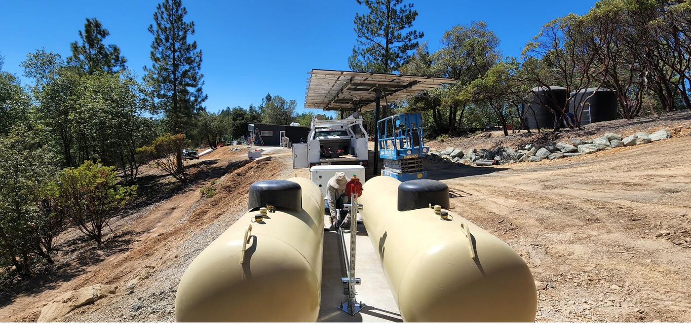 Two propane tanks totaling 660 gallons set on a concrete pad for off-grid heating and backup power