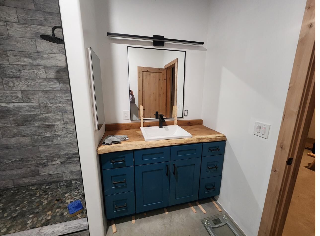 Primary bathroom with live-edge wood countertop and pebble shower floor
