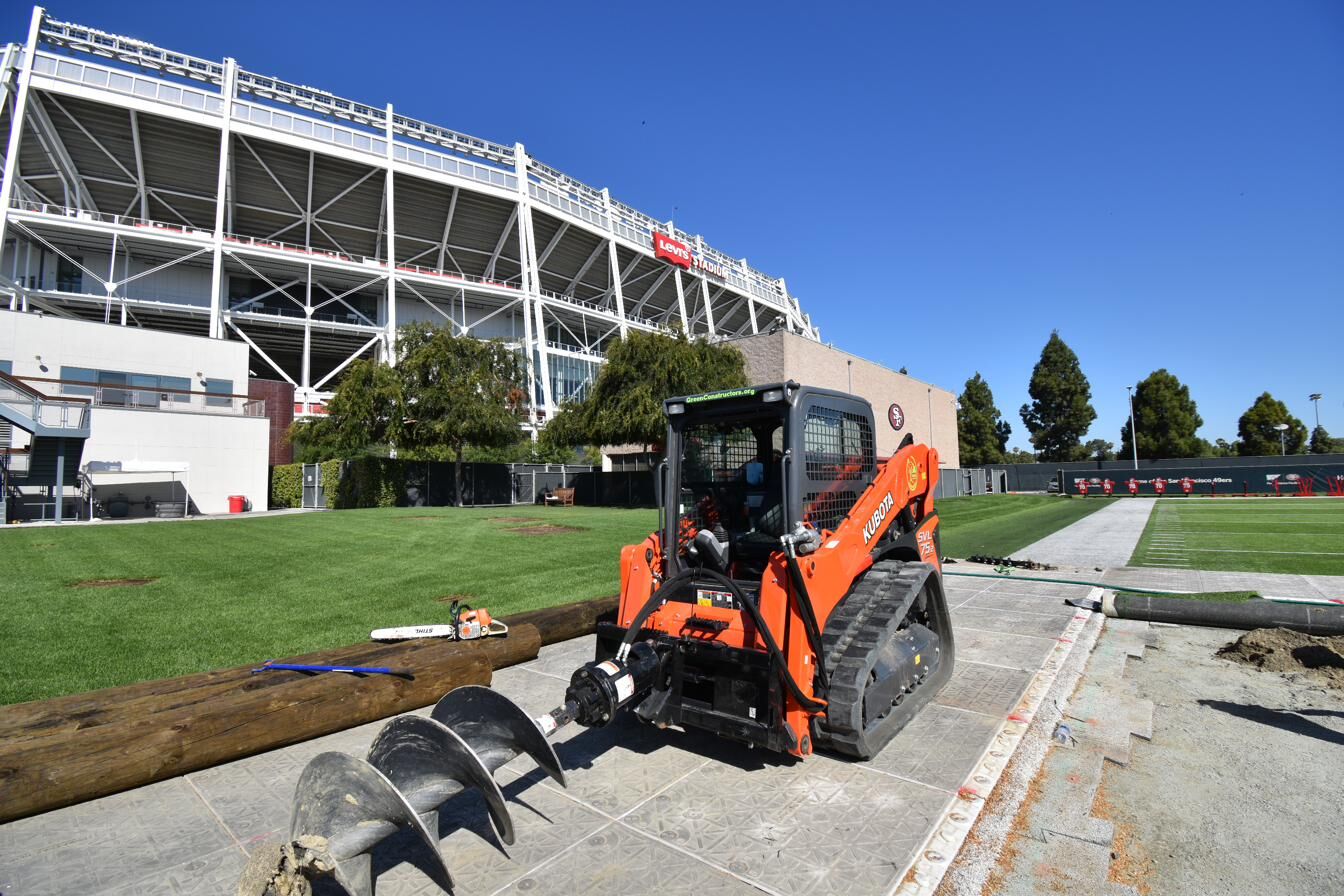 Branded Kubota skid steer with auger attachment drilling post footings at Levi's Stadium