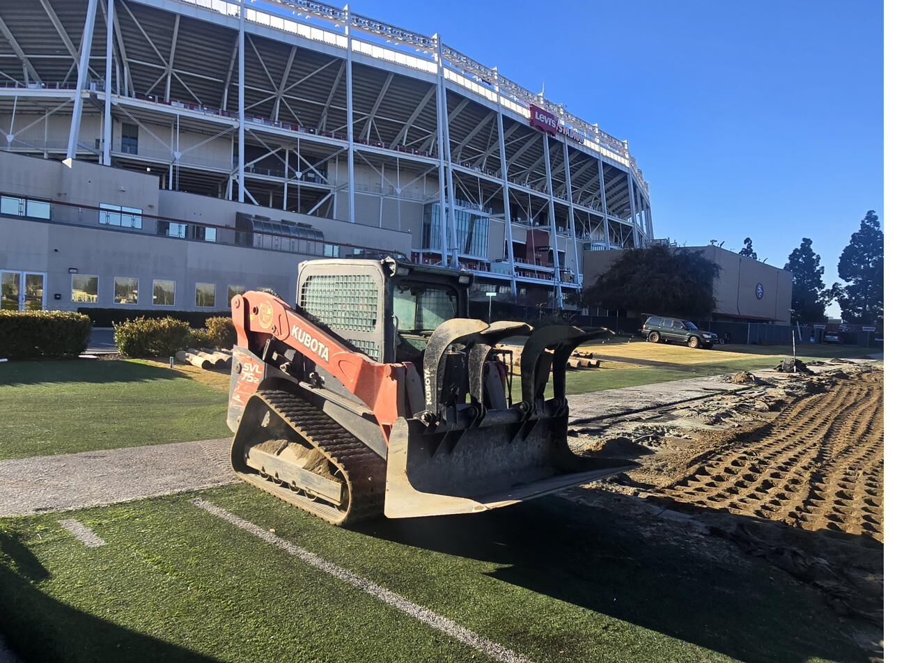 Kubota skid steer on the Levi's Stadium natural grass practice field during 2025 site preparation for the obstacle-course relocation