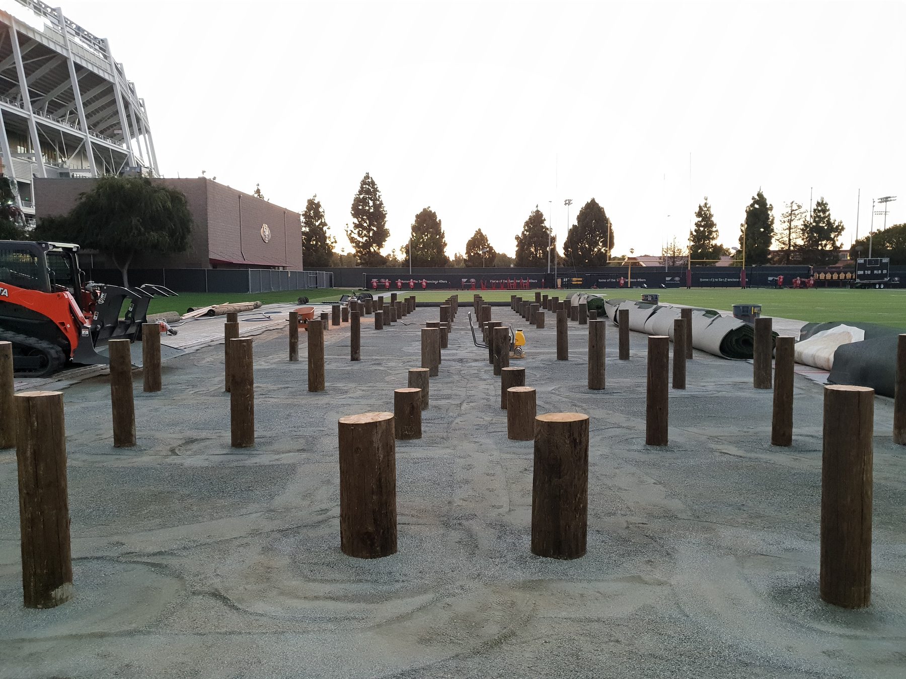 Evening light over the completed obstacle-course posts at Levi's Stadium with a Kubota skid steer in the background
