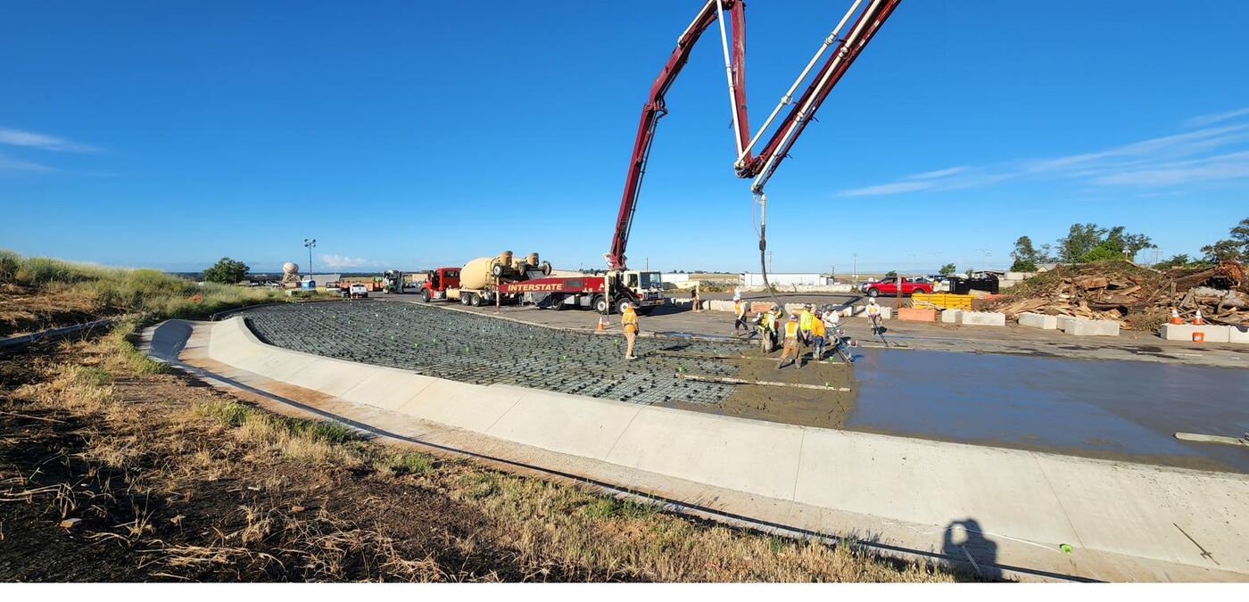 Crew screeding fresh concrete on a large infrastructure slab pour